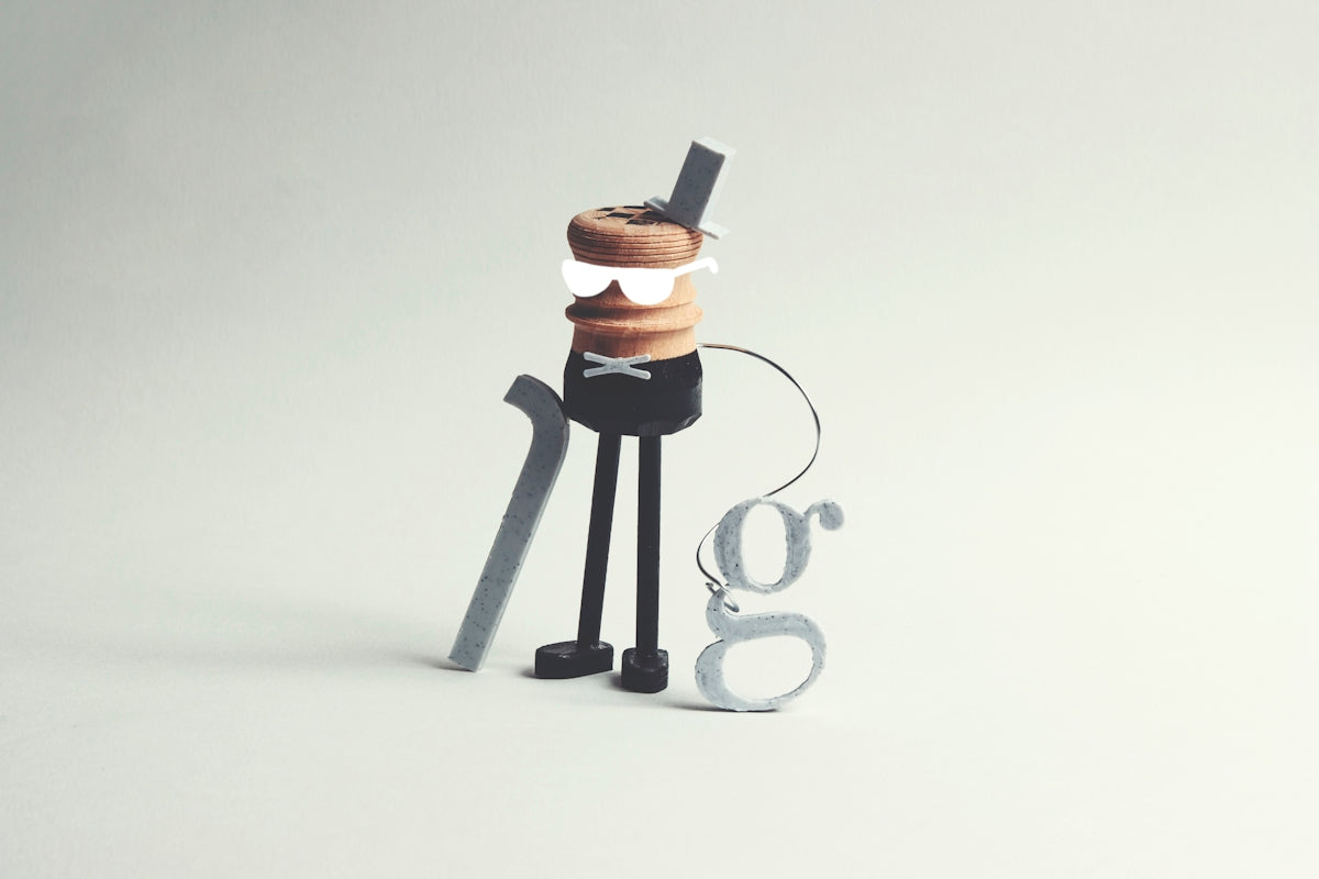 A whimsical character with a cane and letter 'g' accessory.
